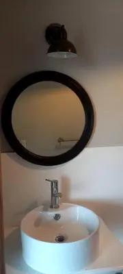 a bathroom sink with a round mirror above it at La casa de Merlot in San Antonio de Arredondo