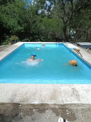 a person in a swimming pool with a hat on at Cabaña El Poeta in Cuesta Blanca