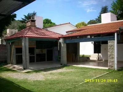 an old house with a red roof and a yard at Casa Doña Victoria in Villa Carlos Paz