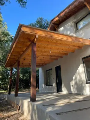 a wooden pergola on the side of a house at Wanna Hospedaje in Villa Ciudad Parque
