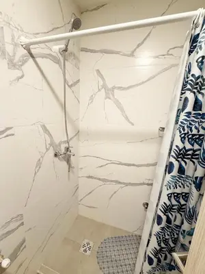 a shower in a bathroom with a marble wall at Edifico NAMBA in Villa Carlos Paz