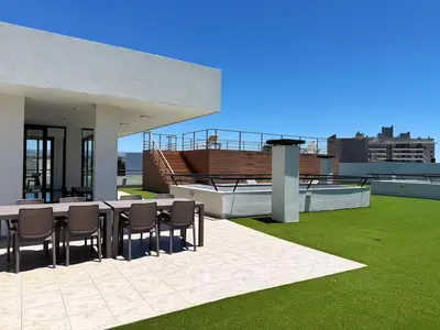 a patio with a table and chairs on a roof at Edifico NAMBA in Villa Carlos Paz
