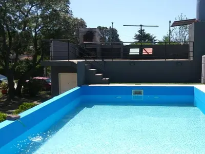 a large blue swimming pool next to a house at complejo Los Ceibos 2 in Villa Carlos Paz