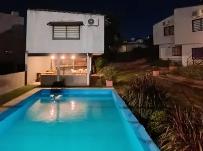 a swimming pool in front of a house at night at complejo Los Ceibos 2 in Villa Carlos Paz