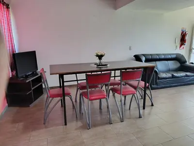 a dining room table with red chairs and a couch at complejo Los Ceibos 2 in Villa Carlos Paz