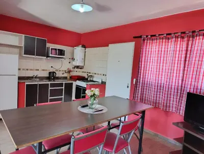 a kitchen with a wooden table and red walls at complejo Los Ceibos 2 in Villa Carlos Paz