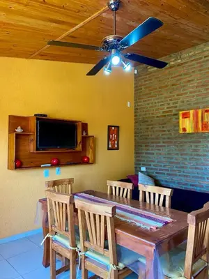 a dining room table with chairs and a ceiling fan at Cabañas LOS NAZARENOS - Villa Quillinzo - CALAMUCHITA in Villa Quillinzo