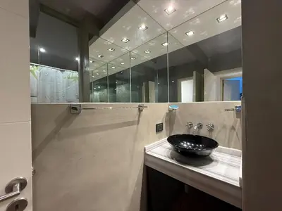 a bathroom with a sink and a large mirror at Moderno Depto 2 dormitorios frente al lago Pileta asador garage in Villa Carlos Paz