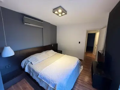 a bedroom with a bed with a blue wall at Moderno Depto 2 dormitorios frente al lago Pileta asador garage in Villa Carlos Paz