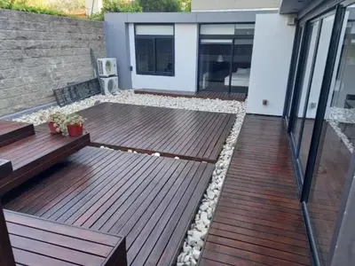 a deck with benches and rocks on a house at Moderno Depto 2 dormitorios frente al lago Pileta asador garage in Villa Carlos Paz