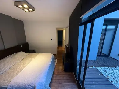 a bedroom with a bed and a balcony with glass walls at Moderno Depto 2 dormitorios frente al lago Pileta asador garage in Villa Carlos Paz