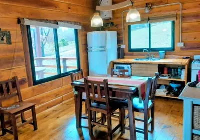 a kitchen with a table and chairs and a refrigerator at Cabaña Don Mario in Villa Yacanto