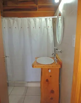 a bathroom with a sink and a white shower curtain at Cabaña Don Mario in Villa Yacanto