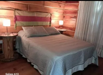 a bedroom with a bed and two tables with lamps at Cabaña Don Mario in Villa Yacanto