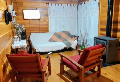 a living room with two chairs and a bed at Cabaña Don Mario in Villa Yacanto