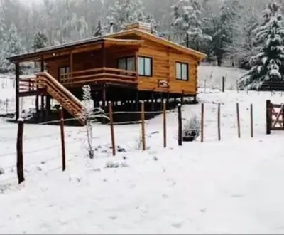 a wooden cabin in the snow with snow covered ground at Cabaña Don Mario in Villa Yacanto
