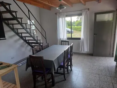 a dining room with a table and chairs and a staircase at Lo de la Abu in Villa de Las Rosas