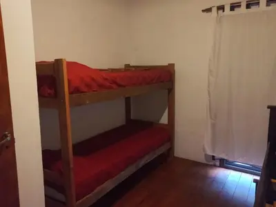 a room with two bunk beds with red sheets at Lo de la Abu in Villa de Las Rosas