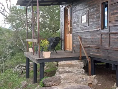 a porch of a log cabin with a table and chairs at Cabaña La Maruca Calamuchita Sierras de Córdoba in San Clemente