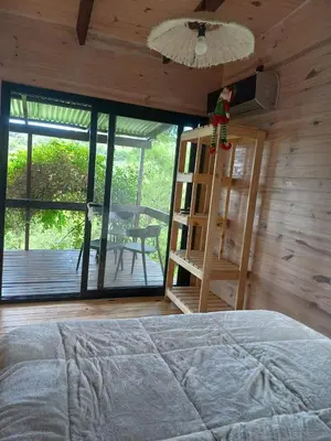 a bedroom with a bed and a book shelf and a table at Cabaña La Maruca Calamuchita Sierras de Córdoba in San Clemente