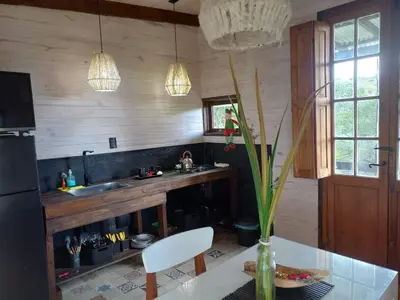 a kitchen with a table and a vase with a plant at Cabaña La Maruca Calamuchita Sierras de Córdoba in San Clemente
