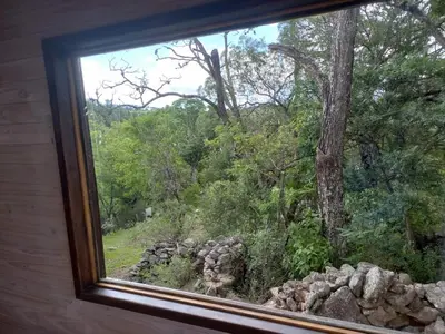 a window with a view of a forest at Cabaña La Maruca Calamuchita Sierras de Córdoba in San Clemente