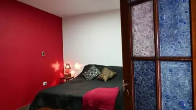 a bedroom with a bed and a red wall at Lucerito no reserve x aca in Villa Santa Cruz del Lago