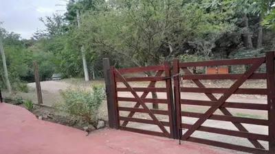 an open gate with a wooden fence in a field at Complejo de cabañas el Winon in Cuesta Blanca