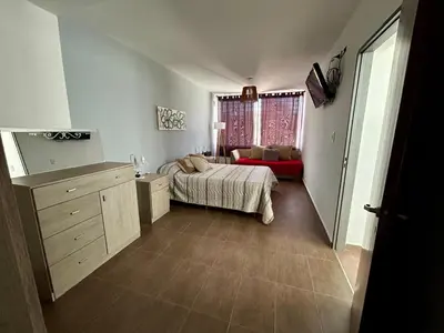 a bedroom with a bed and a red couch at Casita verde in Villa Santa Cruz del Lago
