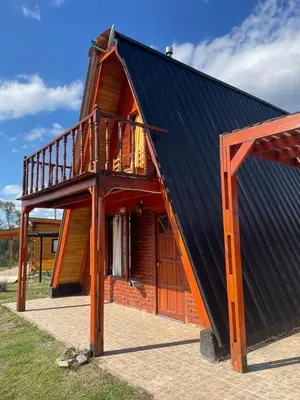 a house with a black roof and a balcony at Cerro del Alma in Villa Yacanto