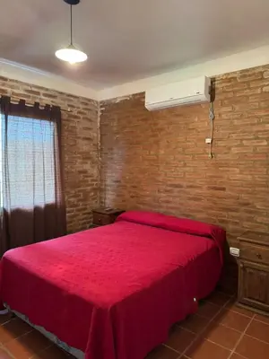 a bedroom with a red bed with a brick wall at El Rincon Verde in Bialet Massé
