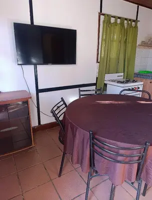 a room with a table and a tv and a table and chairs at Cabañas TUPAC LIHUE in Arroyo de Los Patos