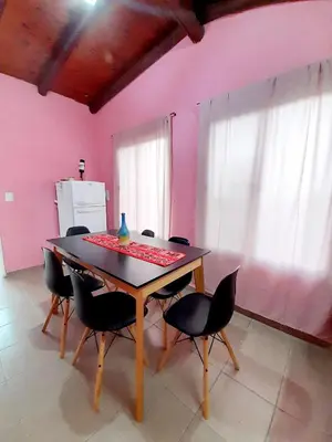 a table and chairs in a room with a pink wall at Brisas de las Sierras in Tanti