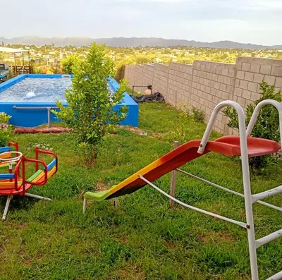 a slide in the grass next to a pool at Brisas de las Sierras in Tanti
