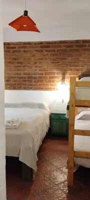 a bedroom with two beds and a brick wall at maemm el castillto in Mina Clavero