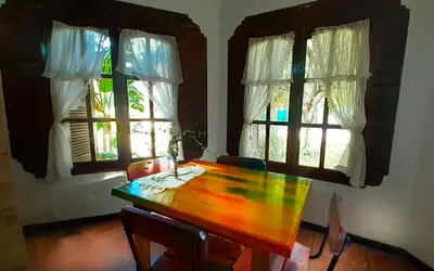 a dining room with a wooden table and two windows at maemm el castillto in Mina Clavero