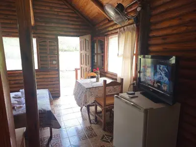 a living room with a table and a television in a cabin at Cabañas Lumel in Carpintería