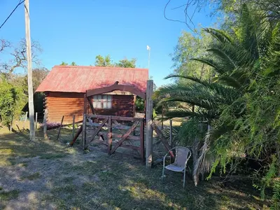 a wooden cabin with a red roof and a chair at Cabañas Lumel in Carpintería