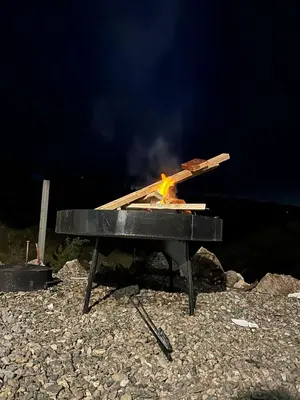 a grill with a fire in it on the beach at ecolodge in San Pedro