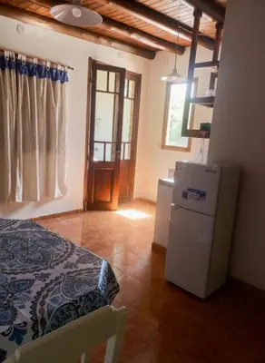 a room with a bed and a refrigerator and a window at Cabaña para 2 Personas en Arroyo de los patos in Arroyo de Los Patos