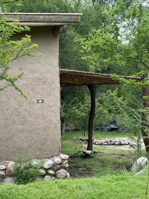 a stone building with a wooden roof in the grass at Espaz in Las Calles