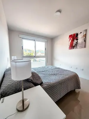 a bedroom with a bed and a lamp on a table at Dpto Carlos Paz - 1 dormitorio con pileta in Villa Carlos Paz