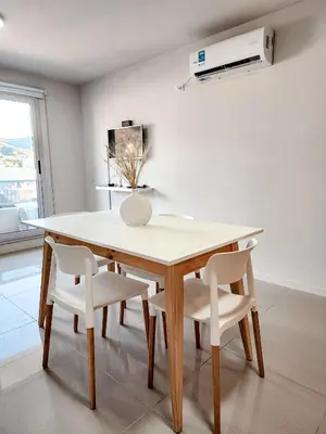 a dining room table with two white chairs and a fan at Dpto Carlos Paz - 1 dormitorio con pileta in Villa Carlos Paz