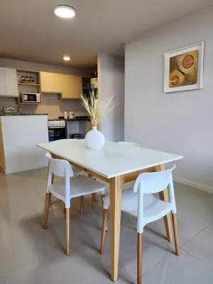 a dining room table with two white chairs and a vase on it at Dpto Carlos Paz - 1 dormitorio con pileta in Villa Carlos Paz