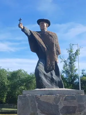 a statue of a man in a hat holding a cross at Cabañas LAS AMELIAS in Villa Cura Brochero