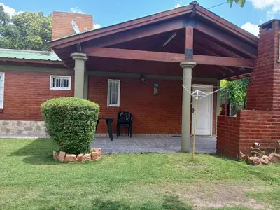 a brick house with a pavilion over a patio at Cabañas LAS AMELIAS in Villa Cura Brochero