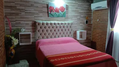 a bedroom with a bed with a pink bedspread at Cabañas LAS AMELIAS in Villa Cura Brochero