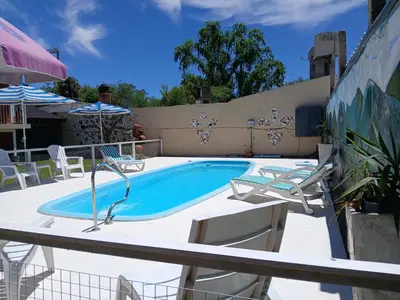 a swimming pool with two lawn chairs and a table at Cabañas LAS AMELIAS in Villa Cura Brochero
