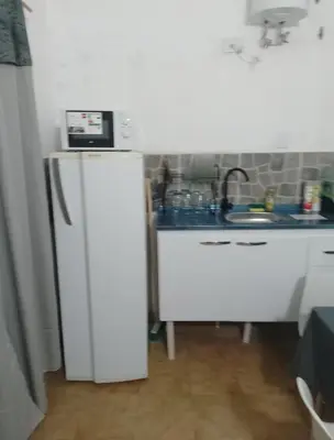 a kitchen with a sink and a microwave on top of a refrigerator at Monoambiente Cerro de las Rosas in Cordoba