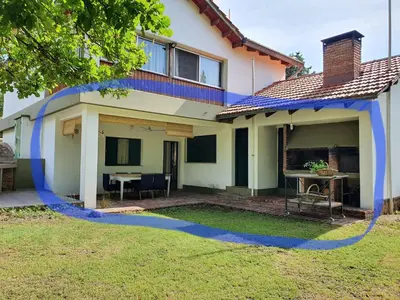 a house with a blue stripe on the front of it at Casa en Nono a 200 metros del lago in Las Rabonas